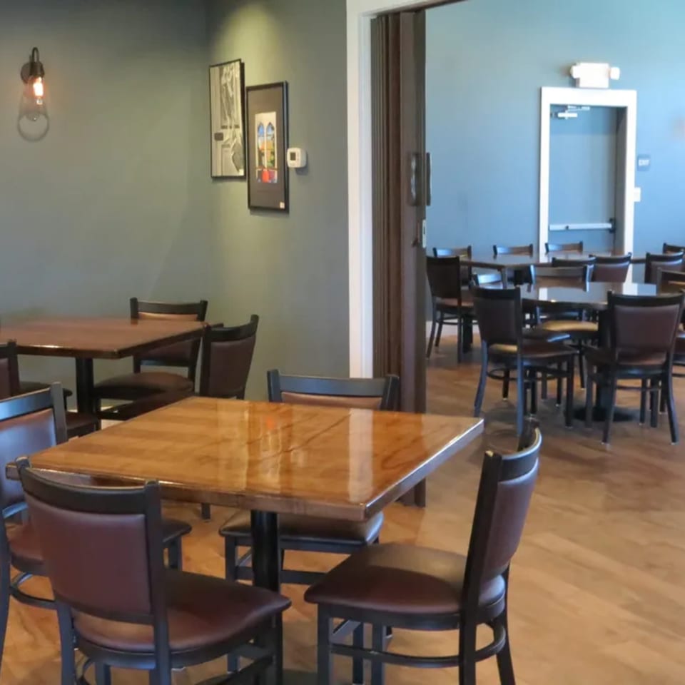 Dining room at Tick Tock's on Terrace with wooden tables, dark chairs, and light green walls.