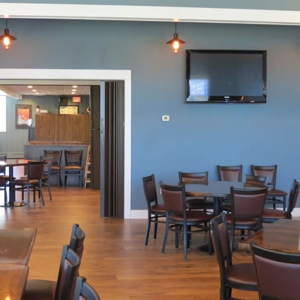Dining area at Tick Tock's on Terrace with blue walls, wooden floors, and dark tables and chairs.